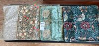 Four pillow covers laid flat showing different William Morris style floral and bird patterns in various classic muted and dark colors.