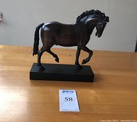 Side view of the wooden trotting horse sculpture showing body and base