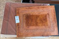 Used tooled leather blotter laid on top, showing embossed decorative border and wear marks