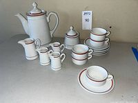 Overview of coffee pot, sugar bowl, four creamers, five cups and saucers