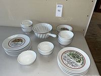 Full view of various bowls, plates, and handle colander in white porcelain with decorative prints
