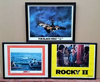 Three framed vintage movie posters on a wall, showing The Black Hole, Jaws 2, and Rocky II.