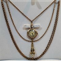 Gold-tone vintage necklace with octagonal watch pendant and decorative cone-shaped drop with faux pearl and red accents, displayed on a white background.