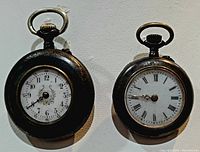 Pair of antique ladies pocket watches showing front views with distinct dials, one with Arabic numerals and floral design, one with Roman numerals.