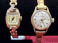 Two vintage wristwatches: one ornate women's watch with curved case and a men's HoVerta automatic watch with date window.