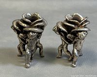 Front view of pair of silver overlay cherub footed rose candleholders.