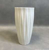 Front view of white porcelain slender vase showing vertical textured ribs and smooth glaze