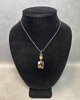 Necklace displayed on black jewelry bust to show pendant and chain length.