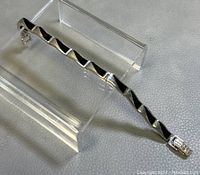 Sterling silver link bracelet laid on a clear acrylic stand showing the overall design and length.