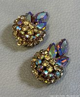 Two vintage Sherman clip-on earrings showing front detail with round and marquise iridescent crystals in gold-tone settings.