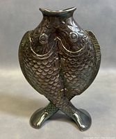 Front view of silver plated bud vase shaped as two fish crossing tails with detailed scales and facial features.