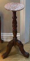 Front view of vintage mahogany carved pedestal plant stand with round marble top and three detailed carved legs.