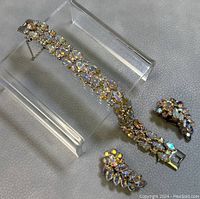 Bracelet and earrings displayed on clear stand showing overall set