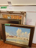 Photo showing four stacked framed artworks showing corner details and frame information including size labels