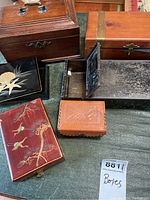 Lot of six decorative boxes including wooden, metal, and leather, placed on a green surface.