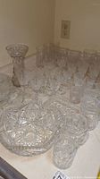 Photo showing a variety of clear crystal glassware including bowls and multiple glasses with cut glass patterns