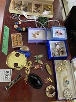 Overall assortment of pins, brooches, necklaces, boxes laid out on table
