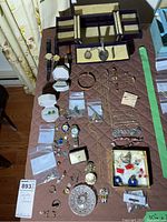 Overview of table with assorted jewelry and two watches displayed next to empty jewelry box