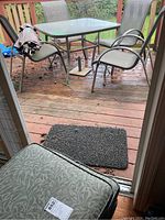 Full patio set including table, four chairs, umbrella, and cushions viewed outdoors on wooden deck.