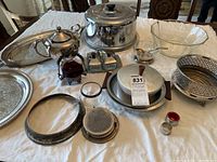 Photo showing full lot on table including metal trays, covered dish with wood handles, glass bowl, small condiment dish, pierced metal round bowl, napkin rings, small red glass condiment container, small metal teapot and other assorted serveware.
