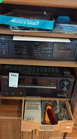 Yamaha KX-W631 double cassette player on top shelf, Onkyo TX-NR656 receiver below, box with cables and VHS cassette cleaning kit at bottom shelf.