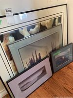 Four framed artworks leaning against a wall showing sizes and framing details.