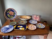 Top view of nine vintage bowls and plates arranged on wooden table showing the variety of designs and colors