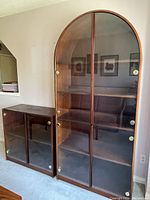 Front view of large and small curio cabinets side by side against a wall