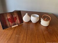 Overall shot of the set including vase, planter, and teapot on wooden table near sign