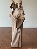 Full front view of the figurine showing both monks in prayer