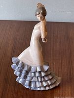 Side view of the flamenco dancer in beige and lavender dress with ruffles, displaying the detailed posture and facial expression.