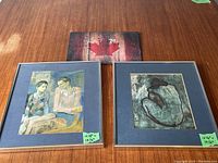 Two framed Picasso prints side by side on wooden table, highlighting blue mattes and silver frames