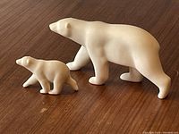 Side view of the two polar bear sculptures on a wooden surface showing the mother and cub figures