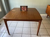 Full front view of square teak table showing tapered legs
