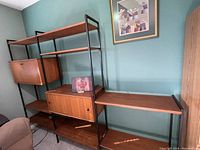 Front view of two tall modules flanking low open shelf section against green wall