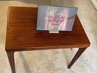Teak side table with visible wood grain and a label indicating lot number and description.