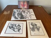 Overview of all three black and white prints on a wooden surface, showing large family group print and two smaller individual prints laid out.