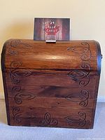 Front view of vintage wooden chest with arched lid and carved decorative folk art designs.