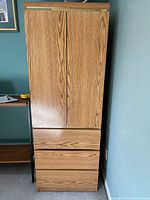 Front view of the wooden wardrobe, closed doors and drawers visible.