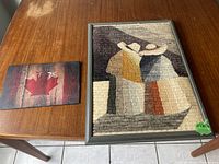 Photo of the framed textile art on a table with a lot number card beside it.
