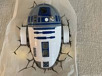 Front view of the R2D2 wall light mounted on a cracked wall effect sticker laid on the carpet.