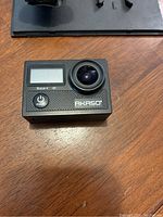 Akaso Brave 4 4K action camera on table, showing front view with lens and LCD screen.