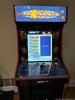 Front view of assembled Arcade1Up cabinet powered on displaying game selection menu.