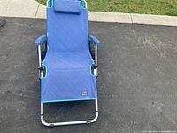 Blue reclinable fabric beach chair with padded headrest, armrests, and aluminum frame shown in upright position.
