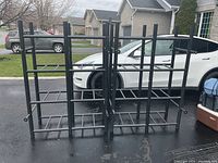 Two assembled black metal storage racks outside on driveway