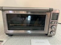 Front view of the Breville Smart Oven Pro showing stainless steel body, glass door, and control knobs.