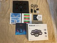 Drone unit with six propellers in hexagonal black frame, two chargers, decal sheets with shark face and stripes, instruction manual, and original box