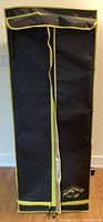 Closed indoor plant growing tent, black with yellow trim, zippered front flap.
