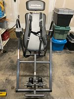 Front view of gray and black Innova inversion table showing padded backrest, headrest, handles, foot holders and frame.