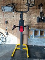 Front view of the multi function station showing pull up bars, padded backrest and yellow base frame.